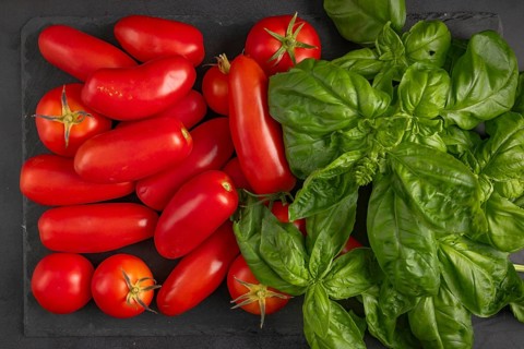Various tomatoes and fresh basil on a slate plate
