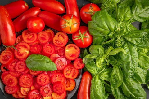 Sliced and whole tomatoes with fresh basil, colourfully presented