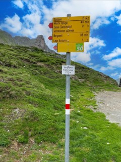 Information board Sign with arrow-shaped signpost at the top of the Splügenpass Passo dello Spluga