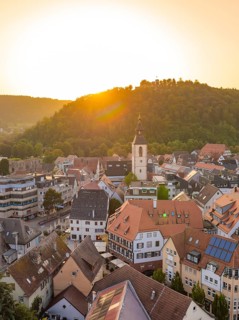 Historic old town with church tower and surrounding hills in the golden evening light, small town