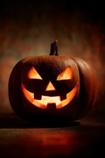 A spooky carved glowing pumpkin in a dark room, symbolising Halloween and autumnal mood, AI