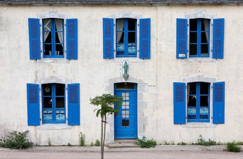 A house with blue shutters and windows, a small tree in front of it, summer atmosphere, Brittany,