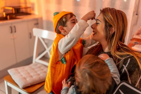 Happy family preparing for a halloween party, applying colorful makeup together at home, creating