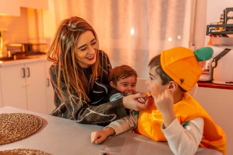 Smiling and playing together in the kitchen, a happy family enjoys halloween festivities while