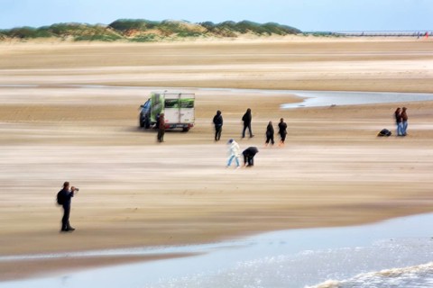 Photographer, walker on the North Sea beach, car, dunes on the horizon, wiping effect, long
