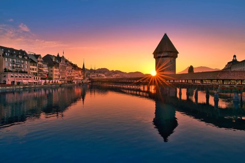 Chapel bridge with water tower reflected in the river Reuss at sunrise, view of Lucerne old town,