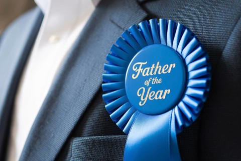 Close up of Father of the Year award ribbon pinned to man's suit chest. Celebration of fatherhood