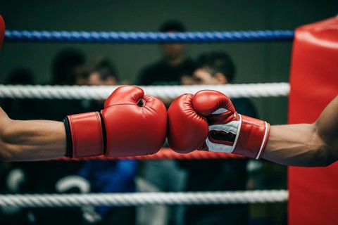 Red boxer's gloved hands touching fists before a spar. Generative ai, AI generated