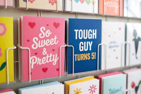 Pink and blue children's greeting cards on a rack. Gender stereotypes and societal expectations
