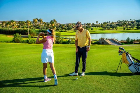 Golfer practicing her swing with coach on beautiful golf course, working on improving her technique