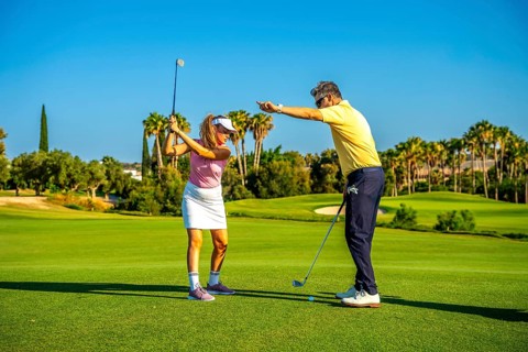 Experienced golf instructor guiding a female golfer on a sunny day, providing tips for a perfect