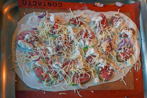 Tarte flambée with figs, onions and two types of cheese on a baking tray in the oven,