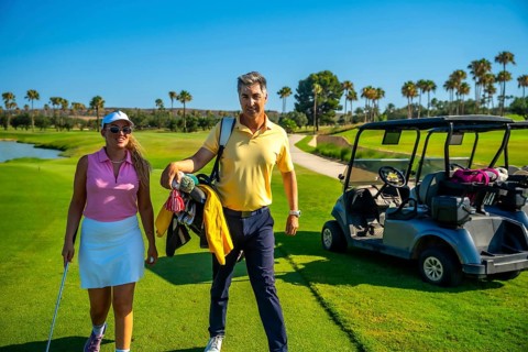 Golfers walking along a stunning golf course, enjoying the sunny day, with a golf cart parked