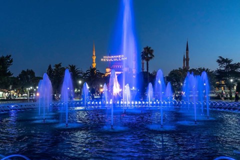 Majestic mosque providing a backdrop to illuminated fountains, creating a captivating scene in