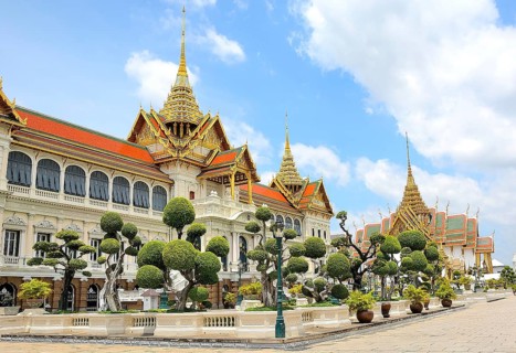Ornate buildings with golden roofs and decorative elements stand amidst manicured gardens,