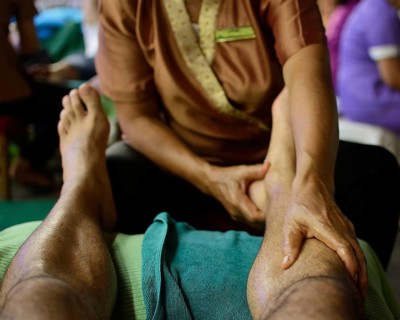 Close up of a thai masseuse performing a relaxing leg massage on a tourist, showcasing the