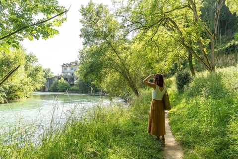 Woman enjoying a sunny day walking along the gave d'oloron river in sauveterre de bearn, a