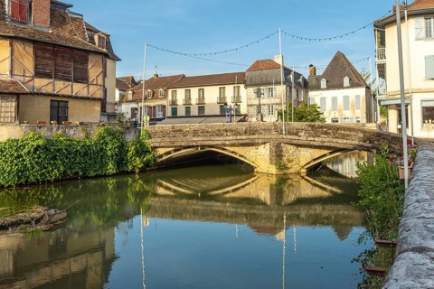Scenic view of the old stone bridge reflecting in the calm river during a sunny morning in the