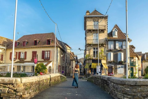 Young woman walking across a bridge in the historic village of salies de bearn, france, enjoying