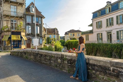 Tourist holding flowers and enjoying the view of a canal in the charming village of salies de