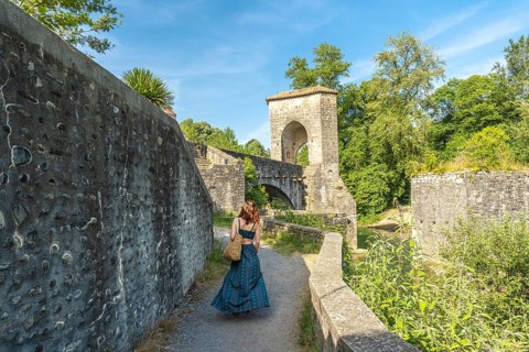 Tourist walking on a sunny day towards the medieval bridge of sauveterre de bearn in france,