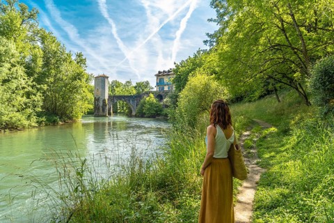 Woman enjoying summer vacations in french countryside admiring the medieval bridge and tower of
