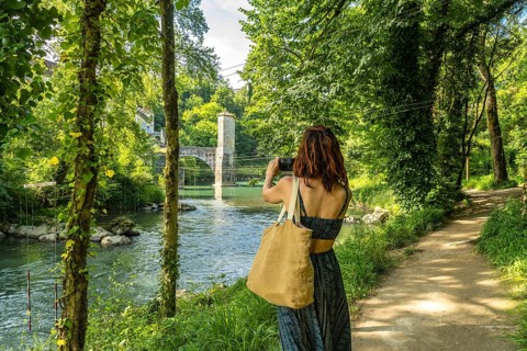 Tourist photographing the gave d'oloron river and its fortified bridge in sauveterre de bearn, a