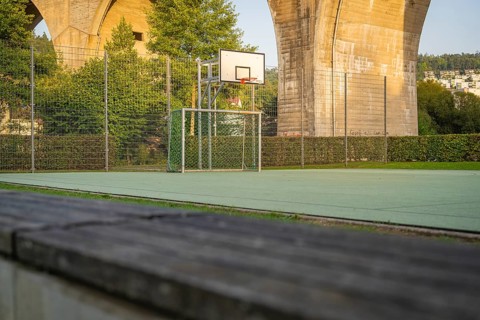 Outdoor basketball court under a large concrete bridge in an urban environment, Nagold, Calw
