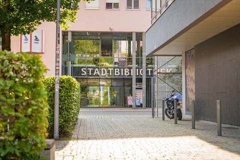 Modern entrance to a municipal library with glass façade and a motorbike in front, Nagold, district