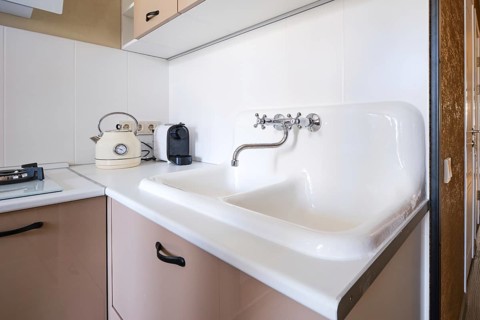 A clean kitchen space features a double sink with a vintage kettle beside a sleek coffee maker.