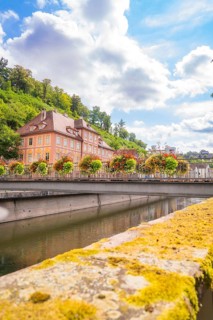 Picturesque riverside with a historic building and lush flowers on the bridge, small town pearl