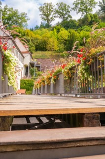 A wooden walkway decorated with flowers leads through a green historical setting, small town of