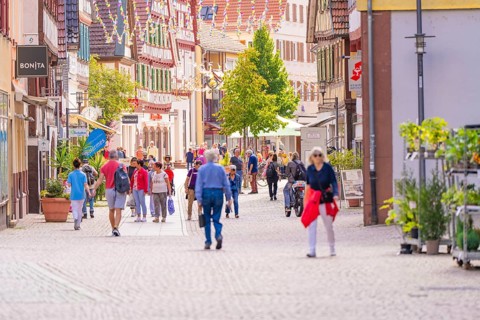 Lively pedestrian zone with people in a town with traditional half-timbered buildings and shops,