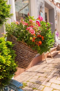 A richly filled basket of flowers on a bicycle handlebar in the sunshine, small town of Perle Calw,