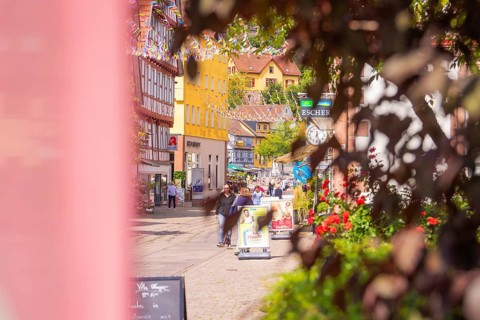 Old town street with full shops and colourful decoration, lively with passers-by, small town pearl