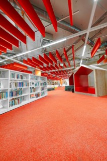 Modern library with red accents, bookshelves and comfortable reading corners, Munich, Germany