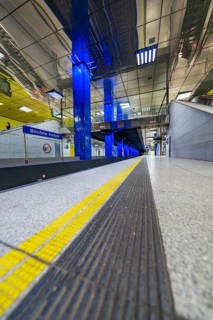 Modern underground station with blue light columns and yellow floor markings, Munich, Germany