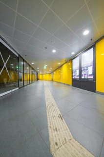 A modern station corridor with yellow walls and a grey floor conveys cleanliness, Munich, Germany