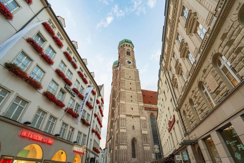 Historically significant church tower surrounded by old buildings under a clear sky, Munich,