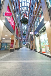 Long shopping arcade with glass roof and illuminated shop windows in an urban atmosphere, Munich,
