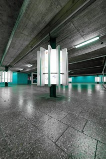 An empty, underground space with concrete walls and glowing green light creates a modern, urban