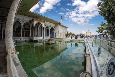 Tourists walking around the courtyard with reflecting pool of the topkapi palace in istanbul,