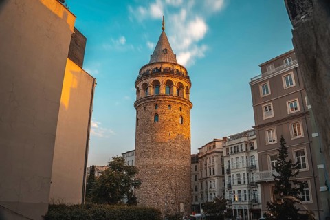 Galata tower, a medieval stone tower, is illuminated by the setting sun in istanbul, turkey,