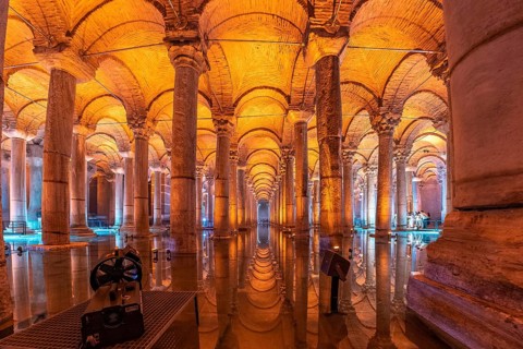 Warm orange light illuminating majestic columns and arches reflecting on the water surface of the