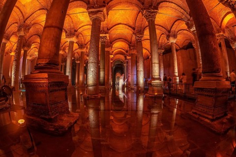 Tourists walking on a walkway in the basilica cistern in istanbul, turkey, with warm light