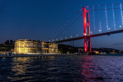 The illuminated suspension bridge over bosphorus strait paints the istanbul night sky red, creating
