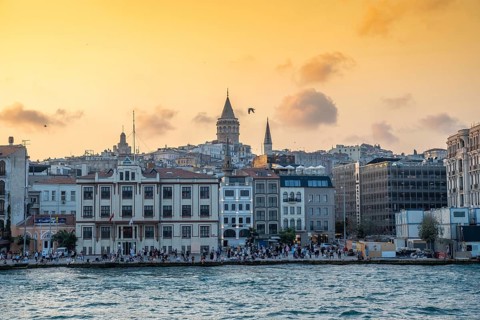 Tourists enjoying sunset view of galata tower and cityscape of istanbul, turkey, from the bosphorus