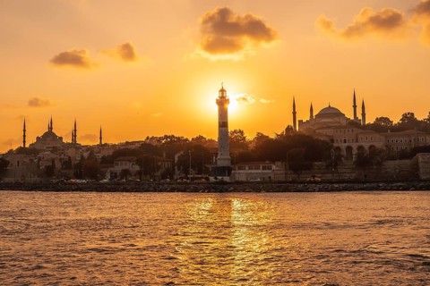 Scenic sunset over istanbul with prominent lighthouse, mosque and hagia sophia silhouettes,