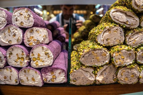 Colorful turkish delight lokum rolls, coated in pistachios and filled with walnuts, stacked on