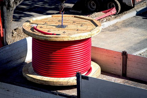 Big red cable coil, rises for installation at the city construction site, no people